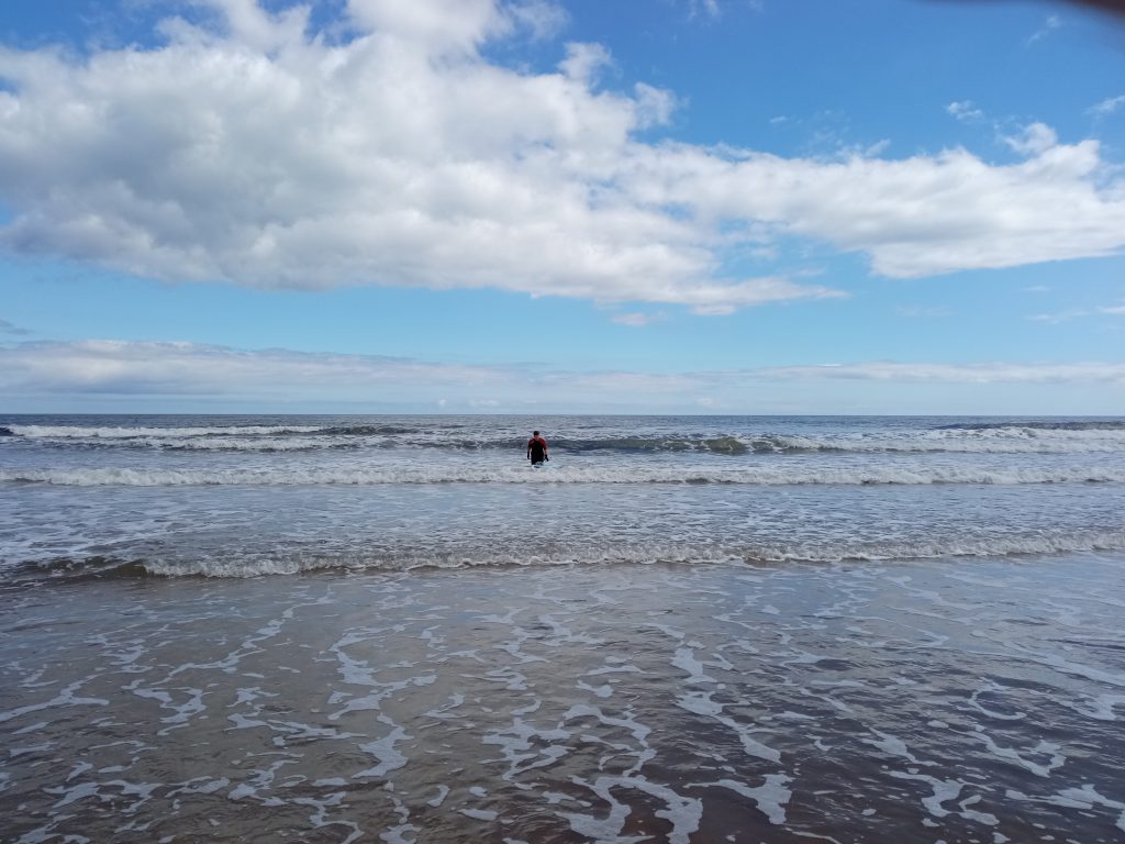 Jelly on a salty plate. A lone surfer walks out of the sea
